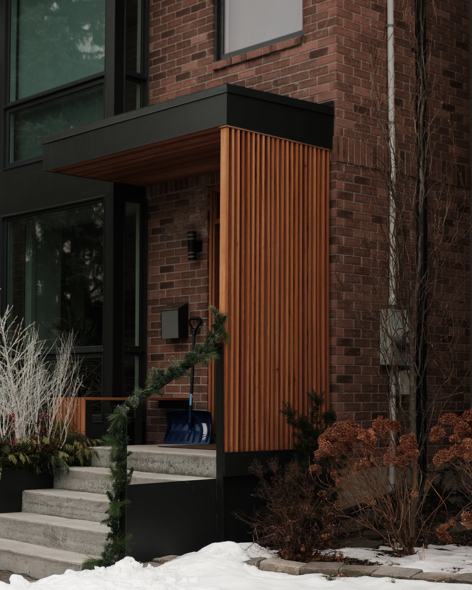 Red brick home with snow shovel by the entrance